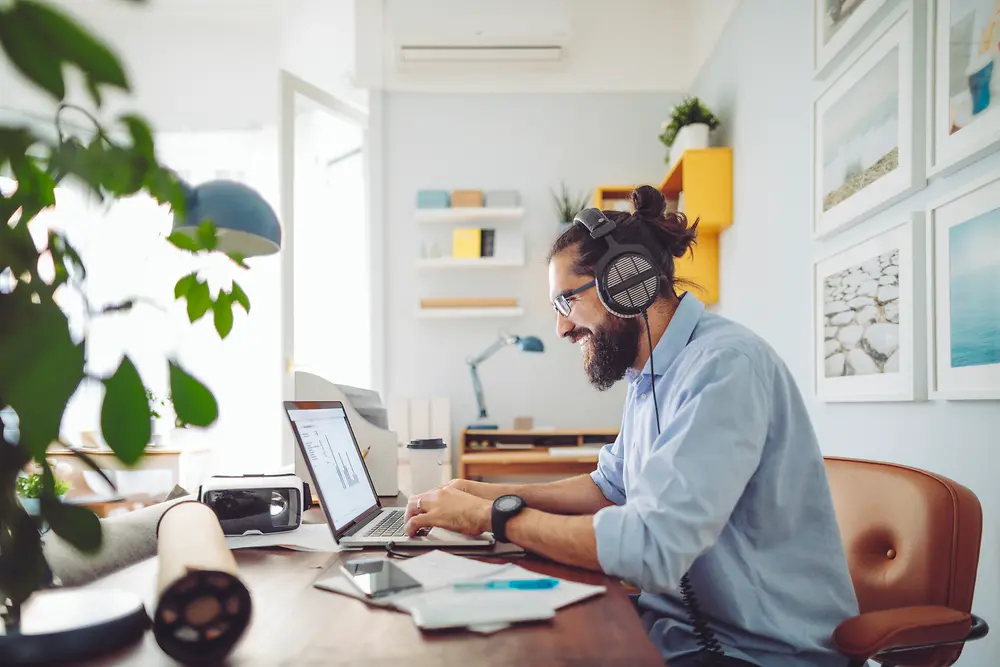 Mann der mit Headset am Schreibtisch sitzt und arbeitet